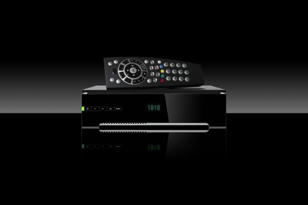 Tv decoder and remote control set on black background.