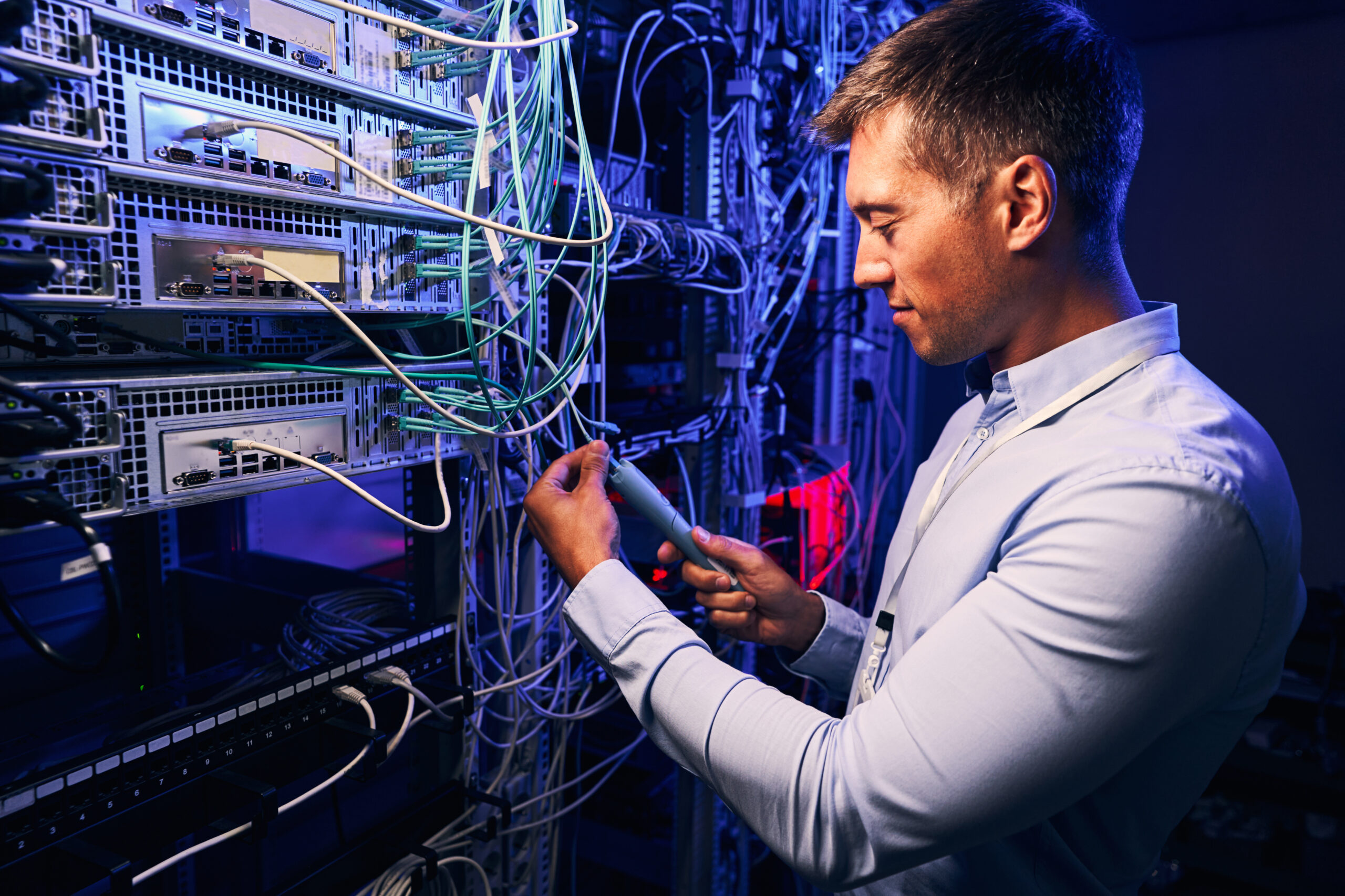 Side view of IT technician performing diagnostic test on fiber optic cables