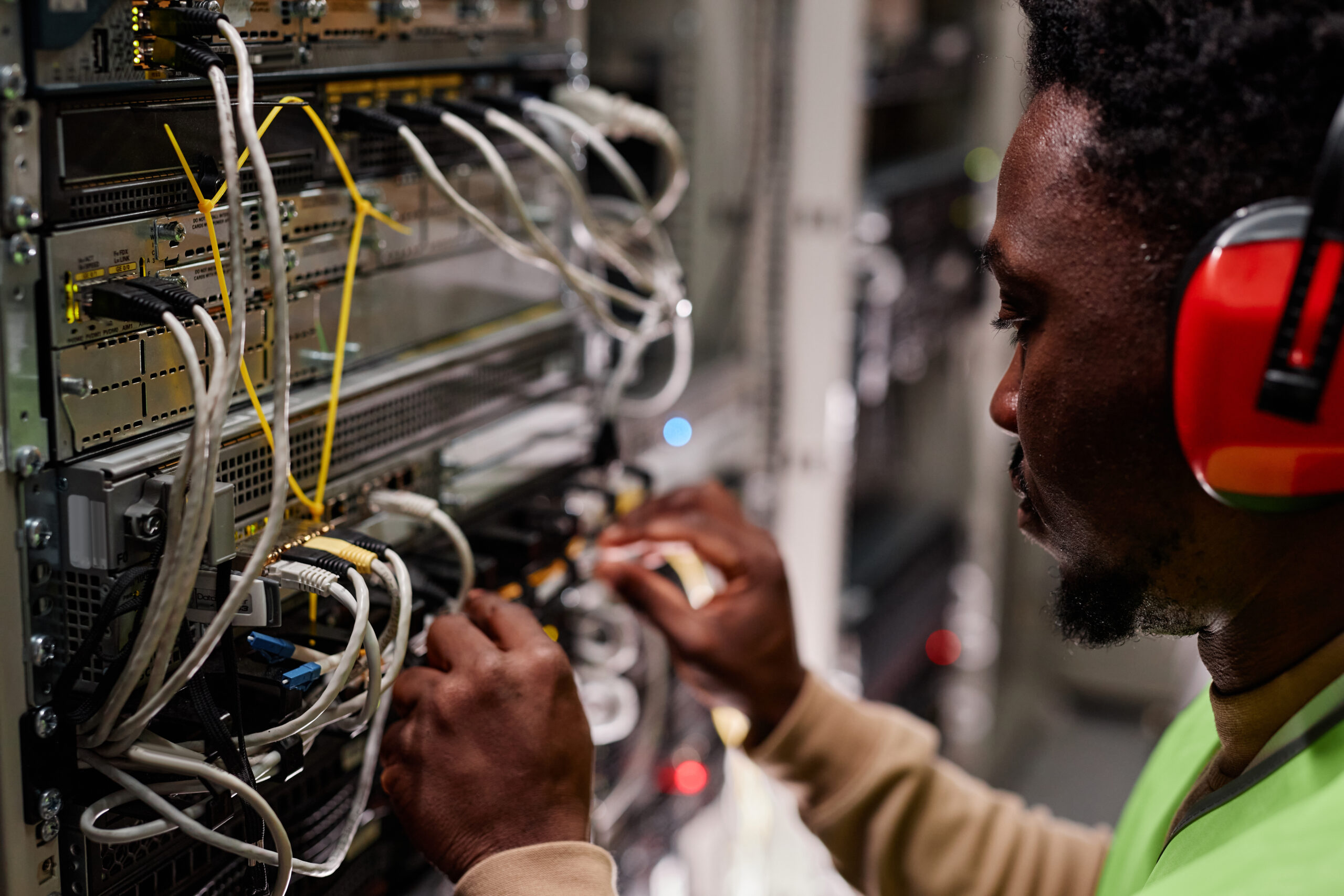 Close up of technician setting up network in server room and wearing ear protection